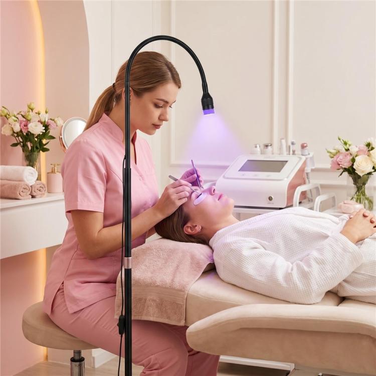 Black floor UV LED curing lamp with glowing bulb during facial lash extension work