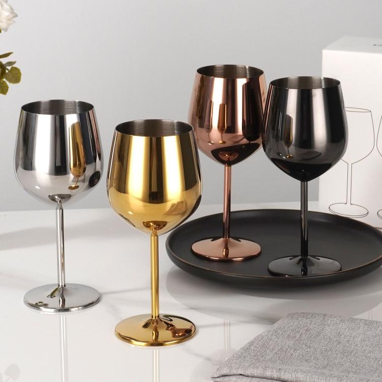 Four metal stemmed wine glasses in silver, black, gold, and copper finishes on tray