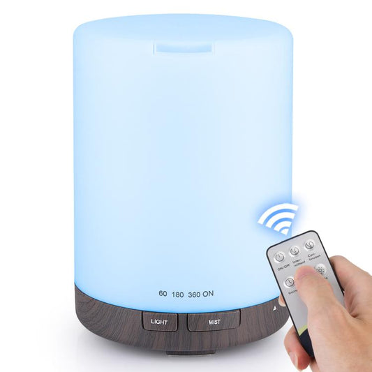 Ultrasonic essential oil diffuser with blue LED glow and dark wood-grain base, shown with remote