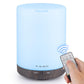 Ultrasonic essential oil diffuser with blue LED glow and dark wood-grain base, remote shown