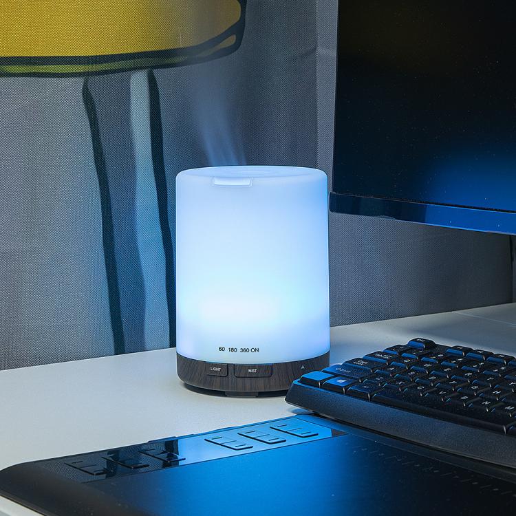 Ultrasonic essential oil diffuser with blue-lit top and dark base, light button