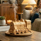 Wood-colored train humidifier releasing mist beside a person on a sofa