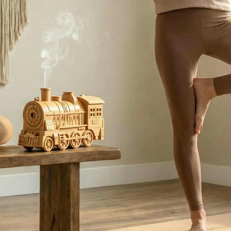 Compact train-shaped humidifier releasing mist on a wooden pedestal