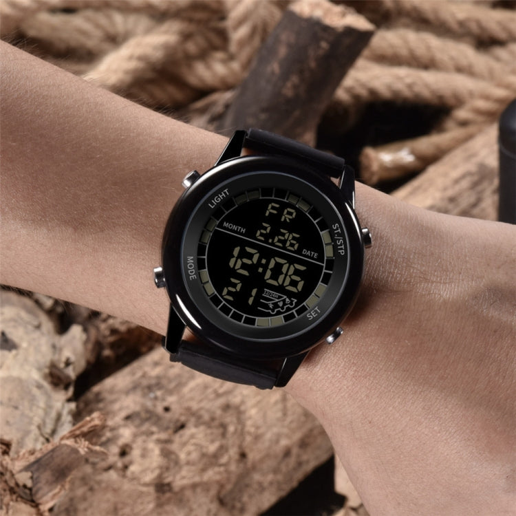 Multifunction digital wrist watch on wrist with black bezel, glowing screen, perforated strap