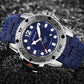 Close-up sports watch with blue dial, thick rugged bezel, and blue silicone link strap.