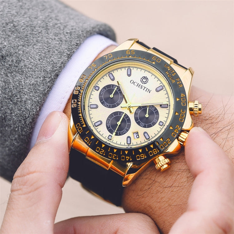 Gold-tone quartz wristwatch with black silicone strap, multi-dial cream face close-up