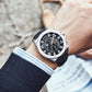 Silver-tone sports watch on wrist with dark strap and black multi-function dial.