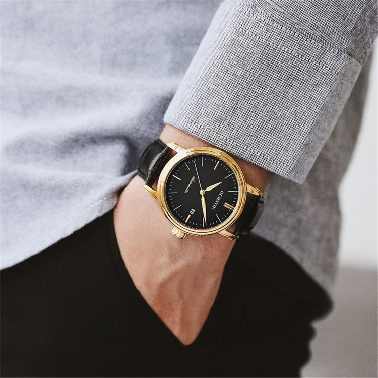 Men's automatic mechanical watch worn on wrist, black dial with gold bezel and black leather strap