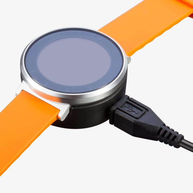 Round watch charging dock clipped onto an orange watch band with cable attached