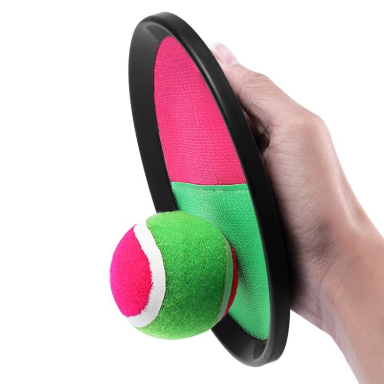 Hand holding round sticky target paddle with neon pink and green foam ball