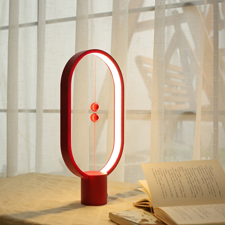 Red oval LED night light with warm glow and three hanging bulb LEDs, on base