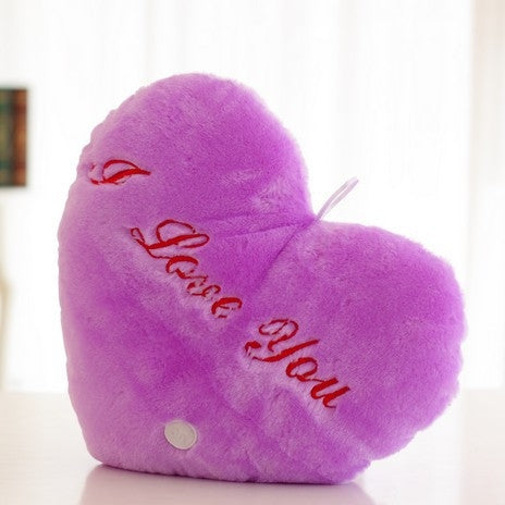 Purple heart-shaped plush glow pillow with red 'I love You' text and button detail