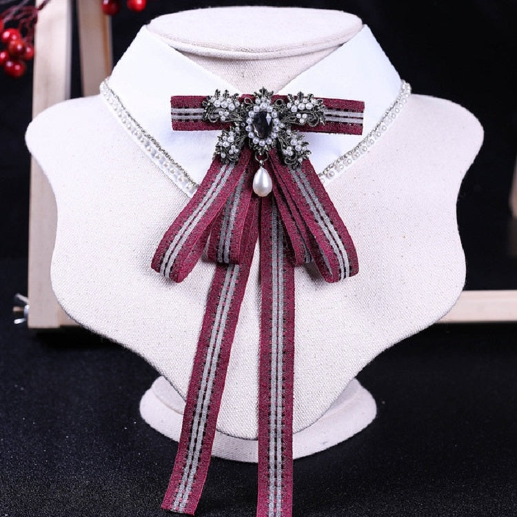 White shirt collar with dark red striped bow tie and rhinestone pearl centerpiece
