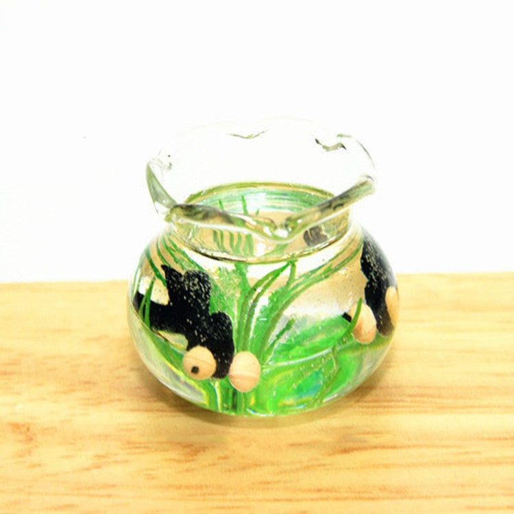 Miniature transparent glass fish tank with green plants and small black fish