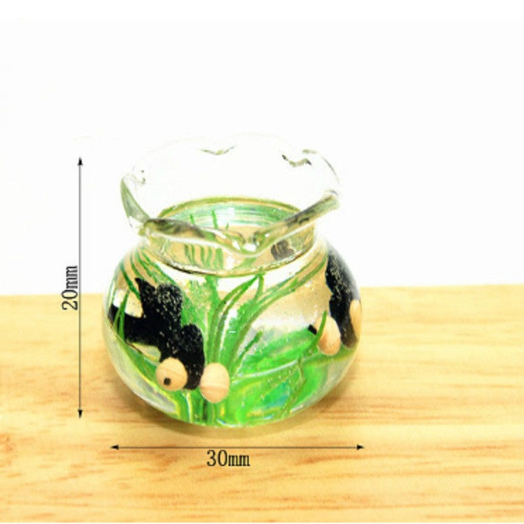 Miniature transparent glass fish tank with green plants and black fish