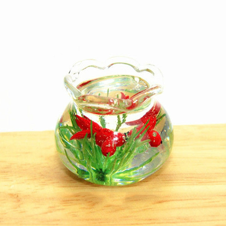 Miniature transparent glass fish tank with green plants and red fish