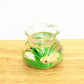 Miniature transparent glass fish tank with green plants and cream-colored fish