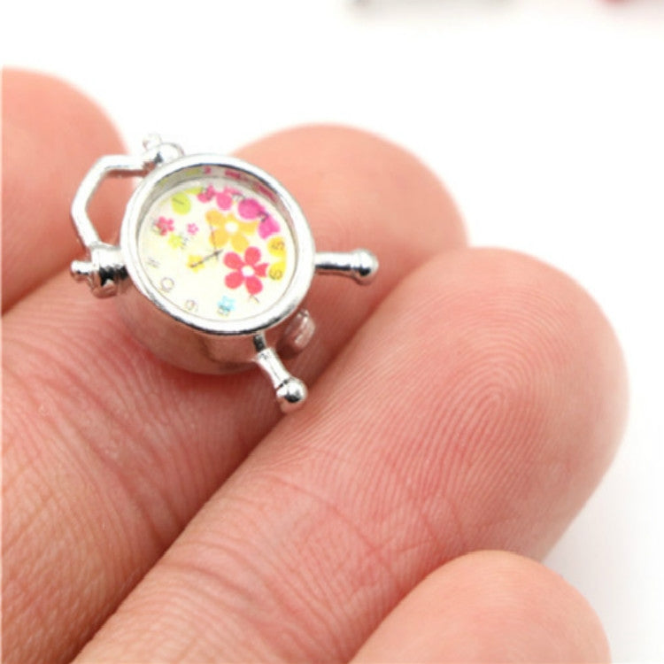 Mini alarm clock accessory with silver frame, floral dial face, and four small legs