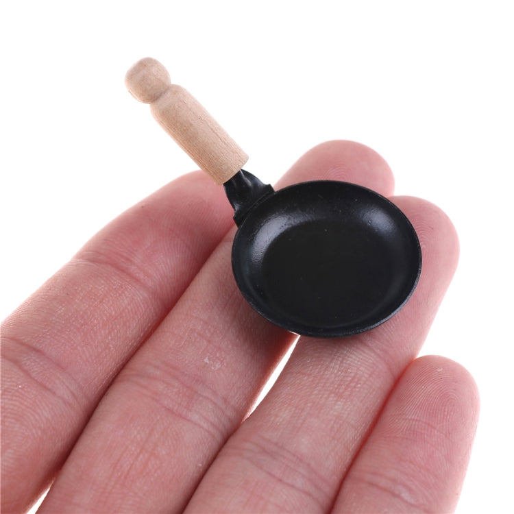 Miniature black frying pan with wooden handle, close-up angled view