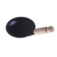 Miniature black frying pan with wooden handle, side view