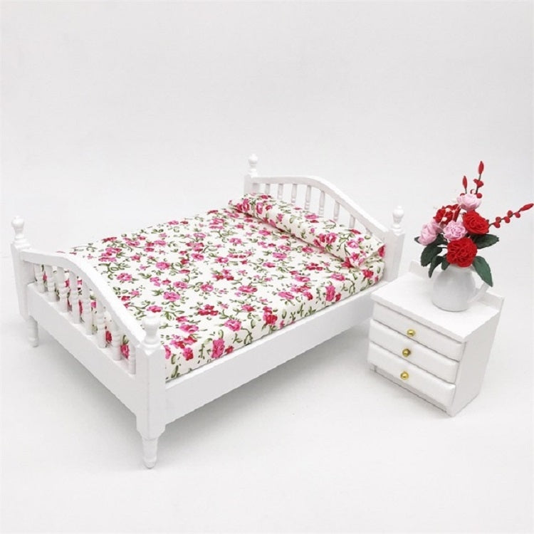 White mini doll bed with pink and green floral bedding and tall headboard