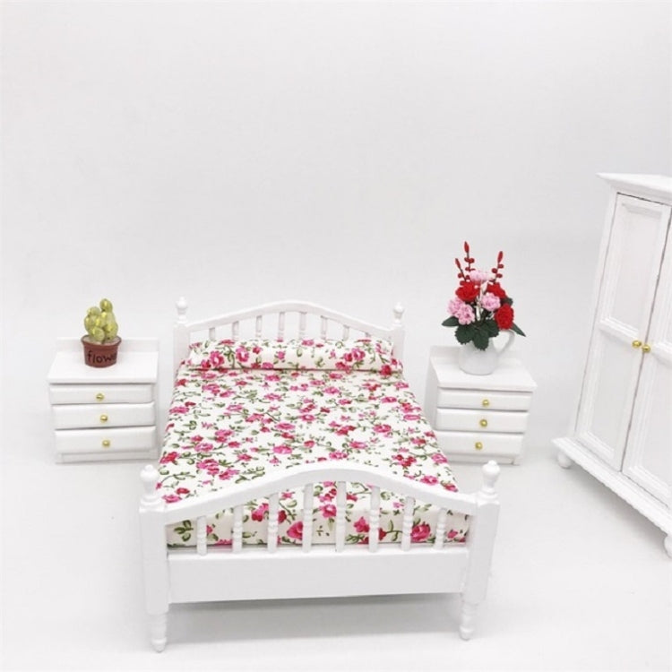 White mini doll bed with floral mattress cover and vertical headboard slats