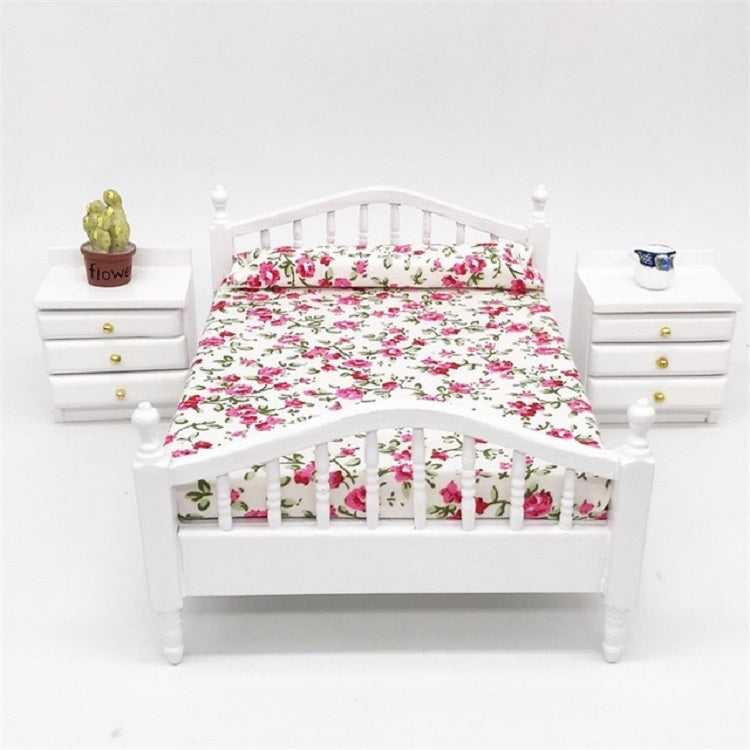 Front view of white mini doll bed with floral bedding and side rail posts