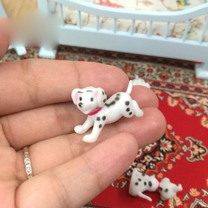 Dalmatian miniature puppy figure with black spots and red collar in a hand
