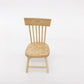 Miniature wooden dollhouse chair with slatted back, round seat, and four legs.