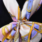 Crystal heart buckle brooch at scarf knot on patterned scarf