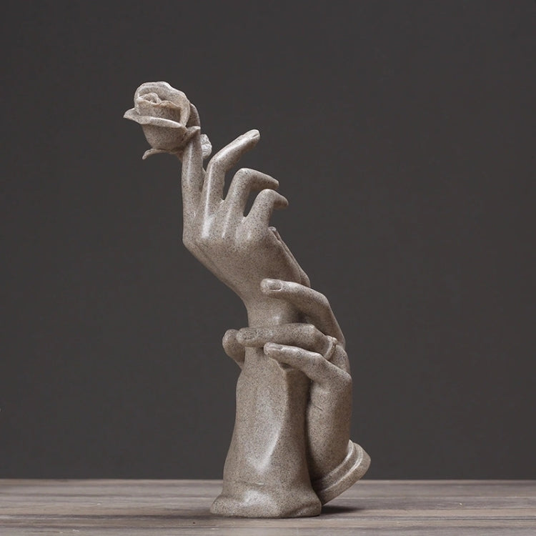 Abstract light-gray sculpted hands holding a small rose, stacked finger details.