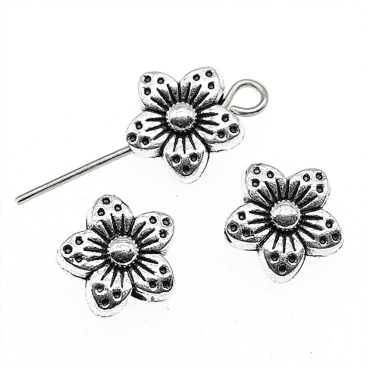 Tibetan-style silver flower spacer charms with detailed petals, round center, and metal loop