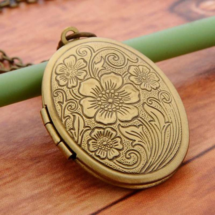 Antique bronze oval locket with engraved floral blossoms and visible hinge clasp