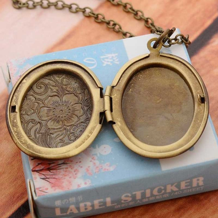 Antique bronze oval locket necklace with open hinged case and engraved floral face