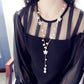 Long pearl necklace with five-petal flower charms and center dangling pearl strand