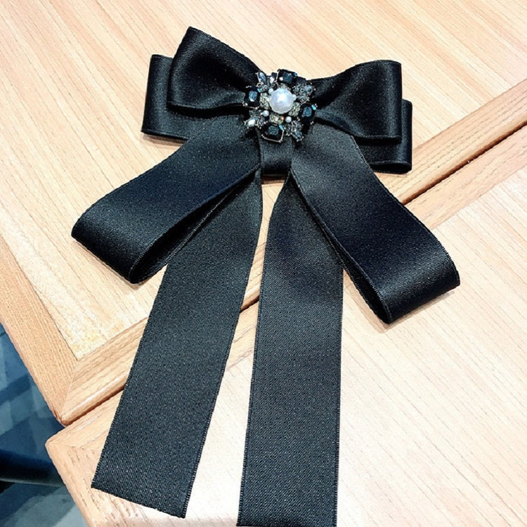 Black satin bow-knot brooch with jeweled centerpiece and long ribbon tails.