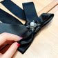 Black satin bow brooch with oval pearl and rhinestone cluster center, pin clasp.