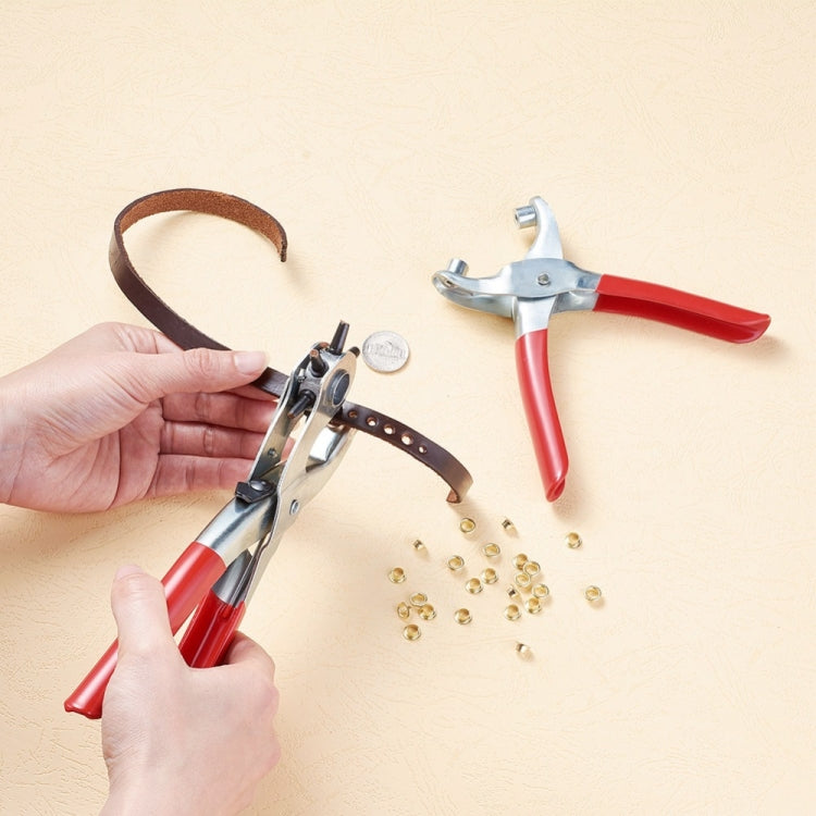 Hand using red eyelet punch pliers on leather strap, with brass eyelets