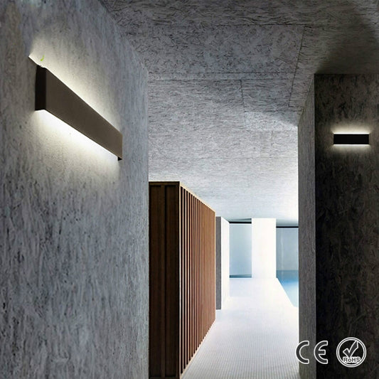 Black linear LED wall sconce with glowing light bar, mounted along a hallway wall.
