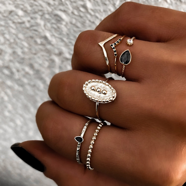 Gold-tone waterdrop and oval rings on hand with black stones and clear details