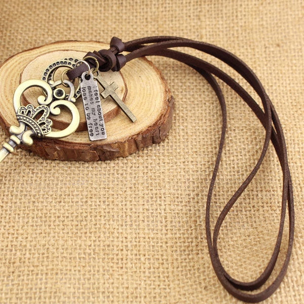 Crown key pendant necklace with heart charm, small cross tag, and key on cord
