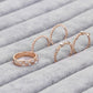 Rose gold rhinestone ring set, four oval bands on gray fabric with small gem accents