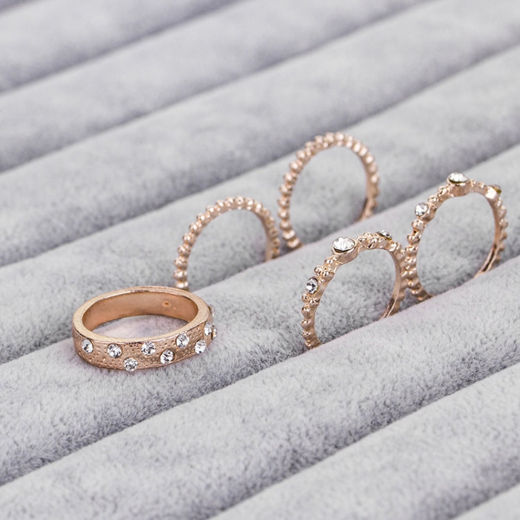 Rose gold rhinestone ring set, four oval bands on gray fabric with small gem accents