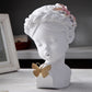 White resin bust statue with closed eyes, floral headpiece, and butterfly charm
