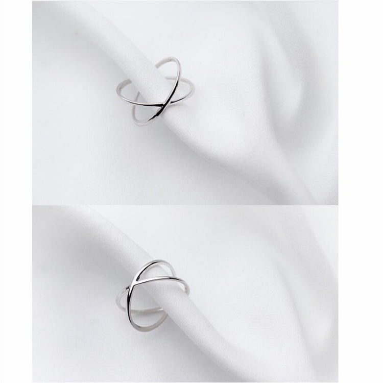 Two views of polished open cross ring on white fabric, slim silver band.