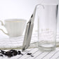 Stainless steel tea infuser pipe set across a clear glass cup