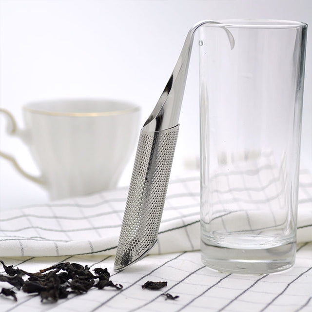 Stainless steel tea infuser pipe set across a clear glass cup