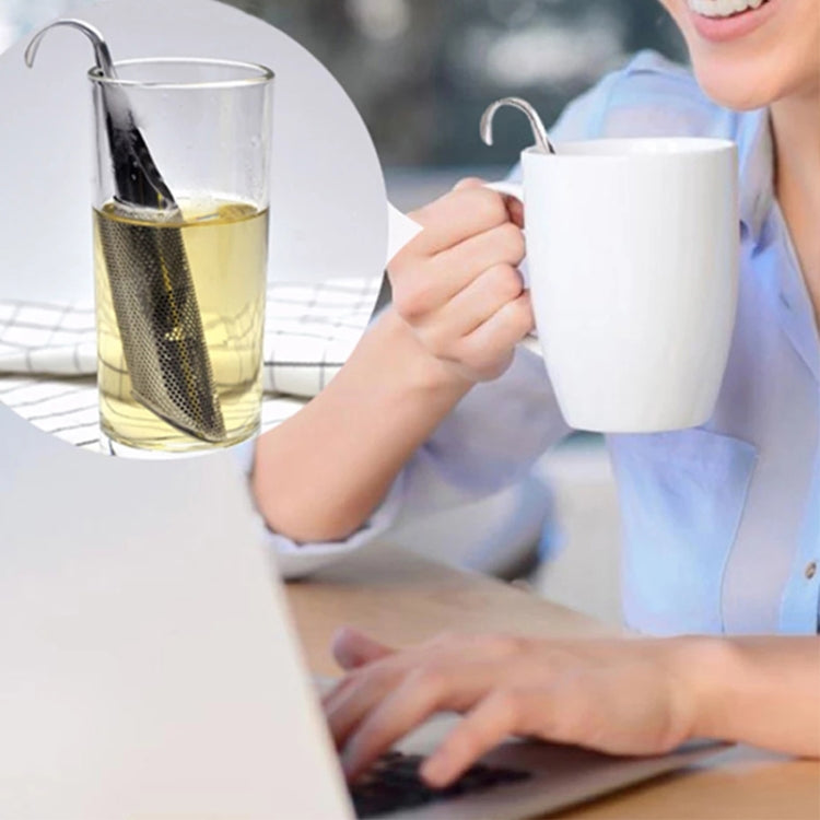 Pipe-shaped stainless steel tea infuser in a cup while held beside a mug