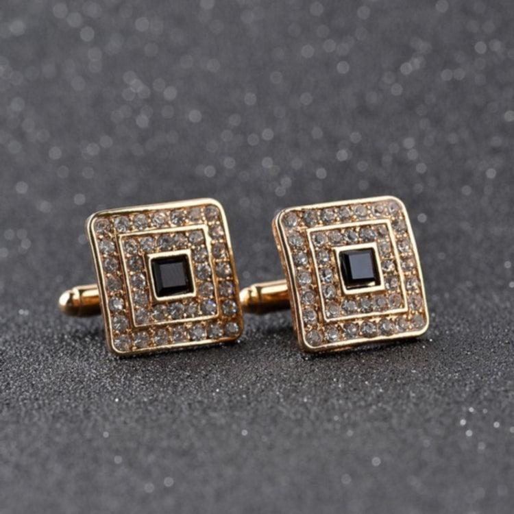 Gold-tone square cufflinks with black center and clear rhinestone border on bar