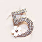 Number 5 rhinestone brooch with white flower accent, rose-gold tone frame